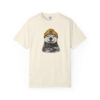Beige t-shirt with a graphic of an otter wearing a cap on a white background